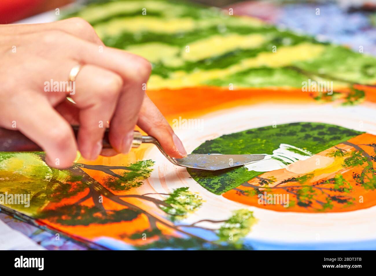 L'artiste peint le paysage dans la gouache à l'aide d'un couteau à mastic. La main de la femme tient la brosse. Gros plan, mise au point sélective Banque D'Images