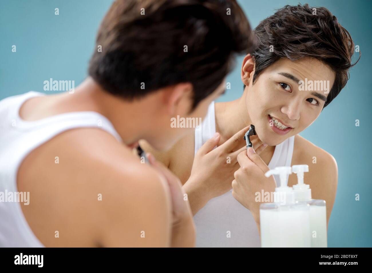 Le jeune homme devant un miroir à raser Banque D'Images