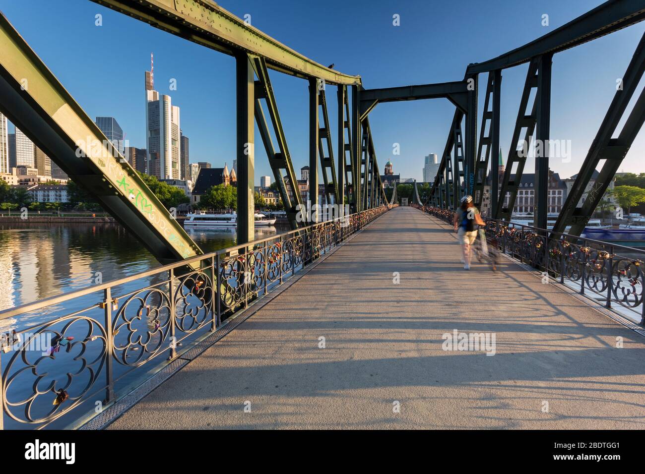 Un cycliste solitaire qui traverse le pont en fer Eiserner Steg à l'aube avec la ligne d'horizon de Francfort comme toile de fond affectueusement connue sous le nom de locks bridged Banque D'Images