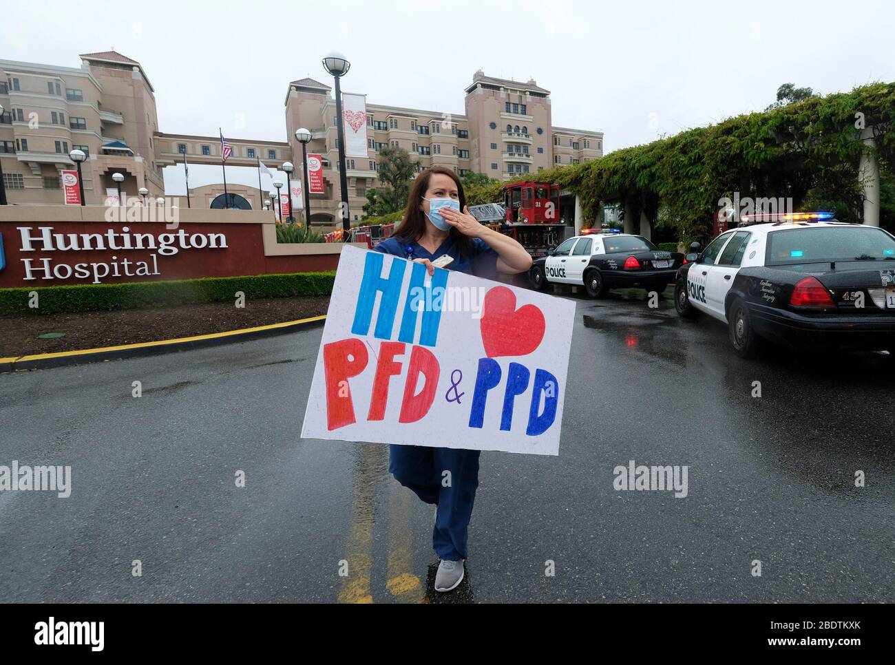 Los Angeles, Californie, États-Unis. 9 avril 2020. Un professionnel de la santé qui tient une pancarte accueille les policiers et le personnel du service d'incendie de Pasadena à l'avant de l'hôpital Huntington avec des lampes d'urgence et des sirènes activées pour montrer leur appréciation aux travailleurs de la santé dans la salle d'urgence et dans tout l'hôpital de Pasadena, Californie, le jeudi 9 avril 2020. Crédit: Ringo Chiu/ZUMA Wire/Alay Live News Banque D'Images