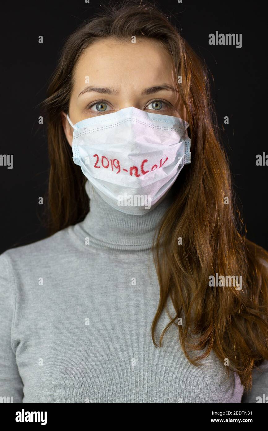 Portrait de la femme effrayée de coronavirus dans le masque médical avec 2019-ncov écrit Banque D'Images