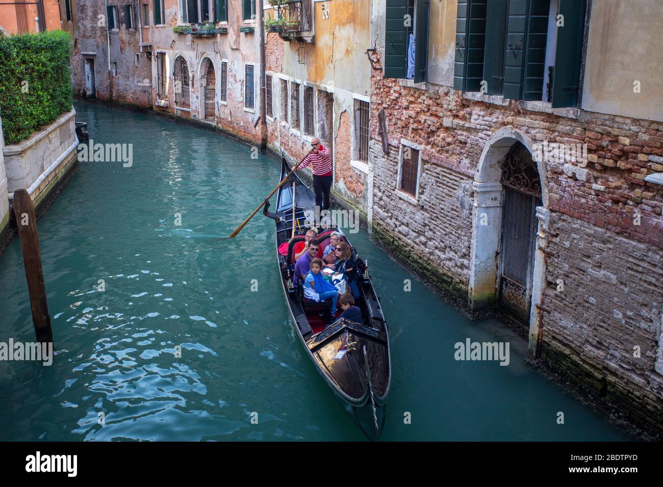 Les touristes voyagent dans une gondole traditionnelle sur un canal vénitien Banque D'Images