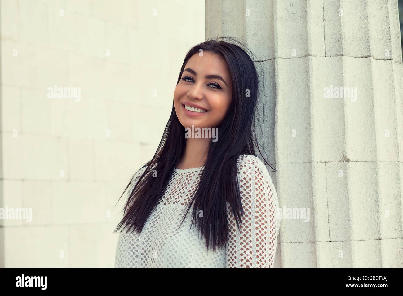 Gros plan portrait de heureuse heureuse heureuse fille indienne en robe blanche, isolé blanc bâtiment colonne fond mur. Humain positif e Banque D'Images Gros plan portrait de heureuse heureuse heureuse fille indienne en robe blanche, isolé blanc bâtiment colonne fond mur. Humain positif e Banque D'Images