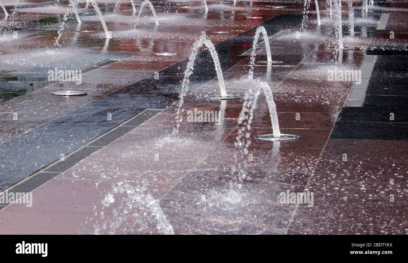Les fontaines voûtées créent un design artistique alors qu'elles bulles contre les places en pierre dans une cour de la ville i Banque D'Images