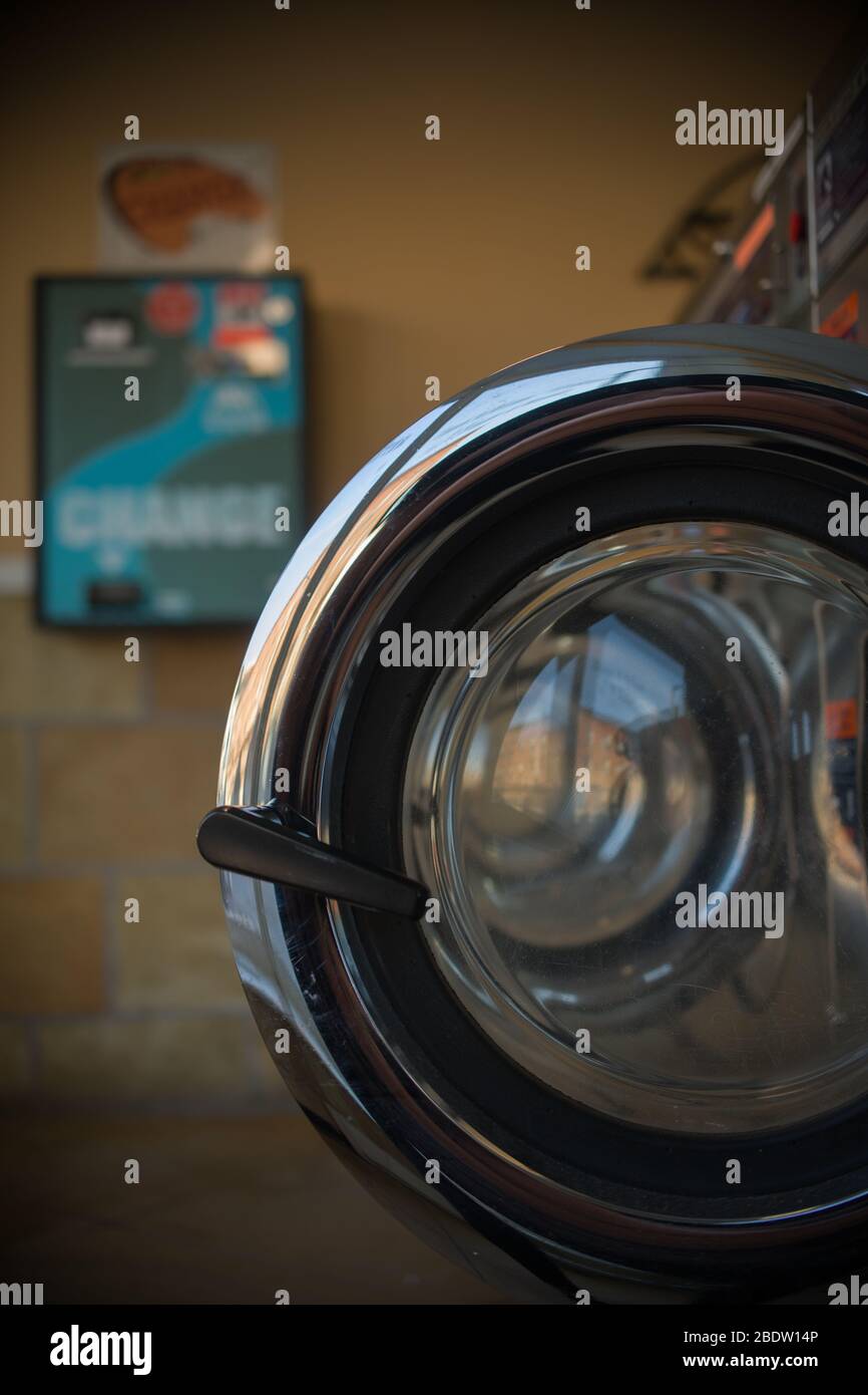 Bonne photo de plusieurs portes ouvertes rondes chromées de sécheurs dans Laundromat avec changement bleu et vert se connecter derrière Banque D'Images