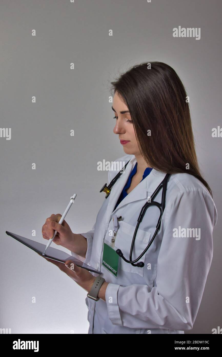 Femme utilisant une tablette dans le secteur de la santé. Pharmacien Lady remplissant les informations de prescription. Stéthoscope sur l'épaule, isolé sur fond gris Banque D'Images