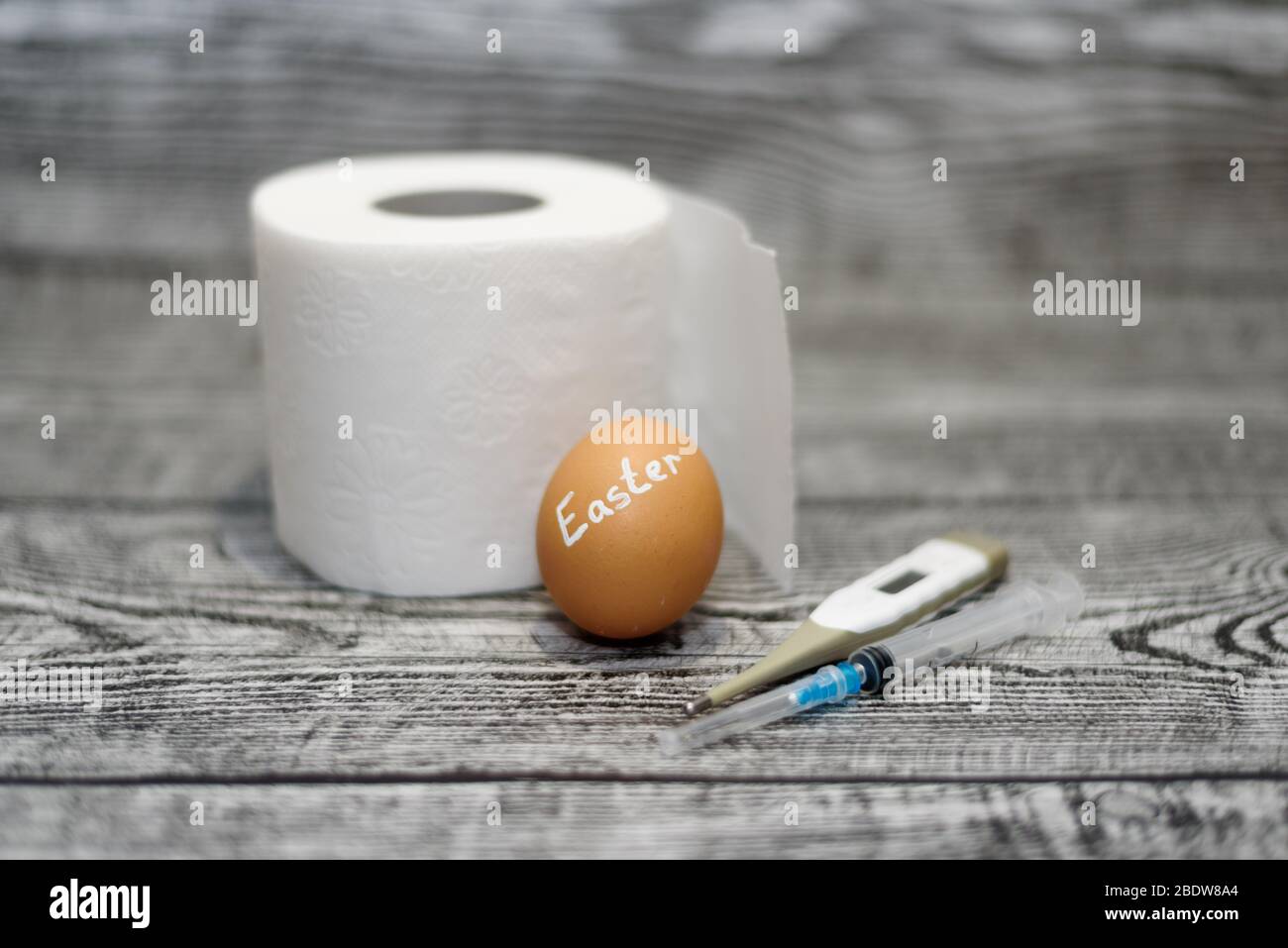 Oeuf de Pâques, papier toilette, thermomètre et seringue sur fond en bois. Coronavirus Covid-19. Photo concept. Pâques 2020. Banque D'Images