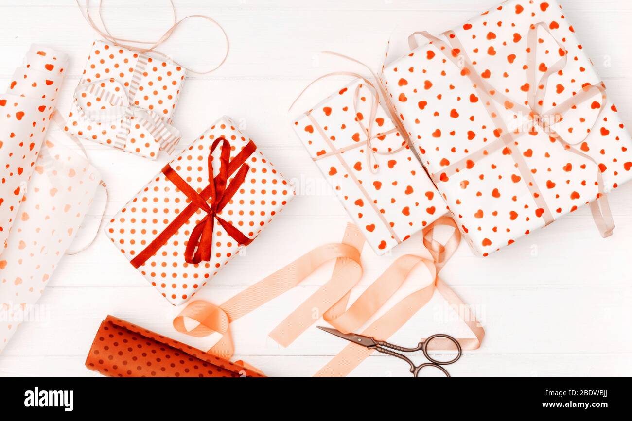 Plat de petits cadeaux enveloppés dans des coeurs à motifs cadeau wrap, ciseaux et ruban en soie Banque D'Images