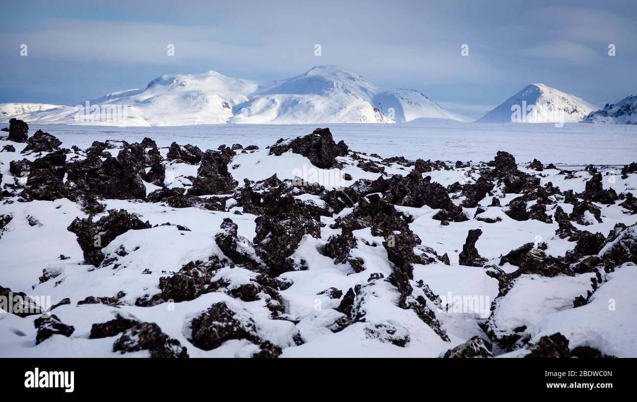 Neige sur un champ de lave avec des montagnes à la distance, Islande Banque D'Images