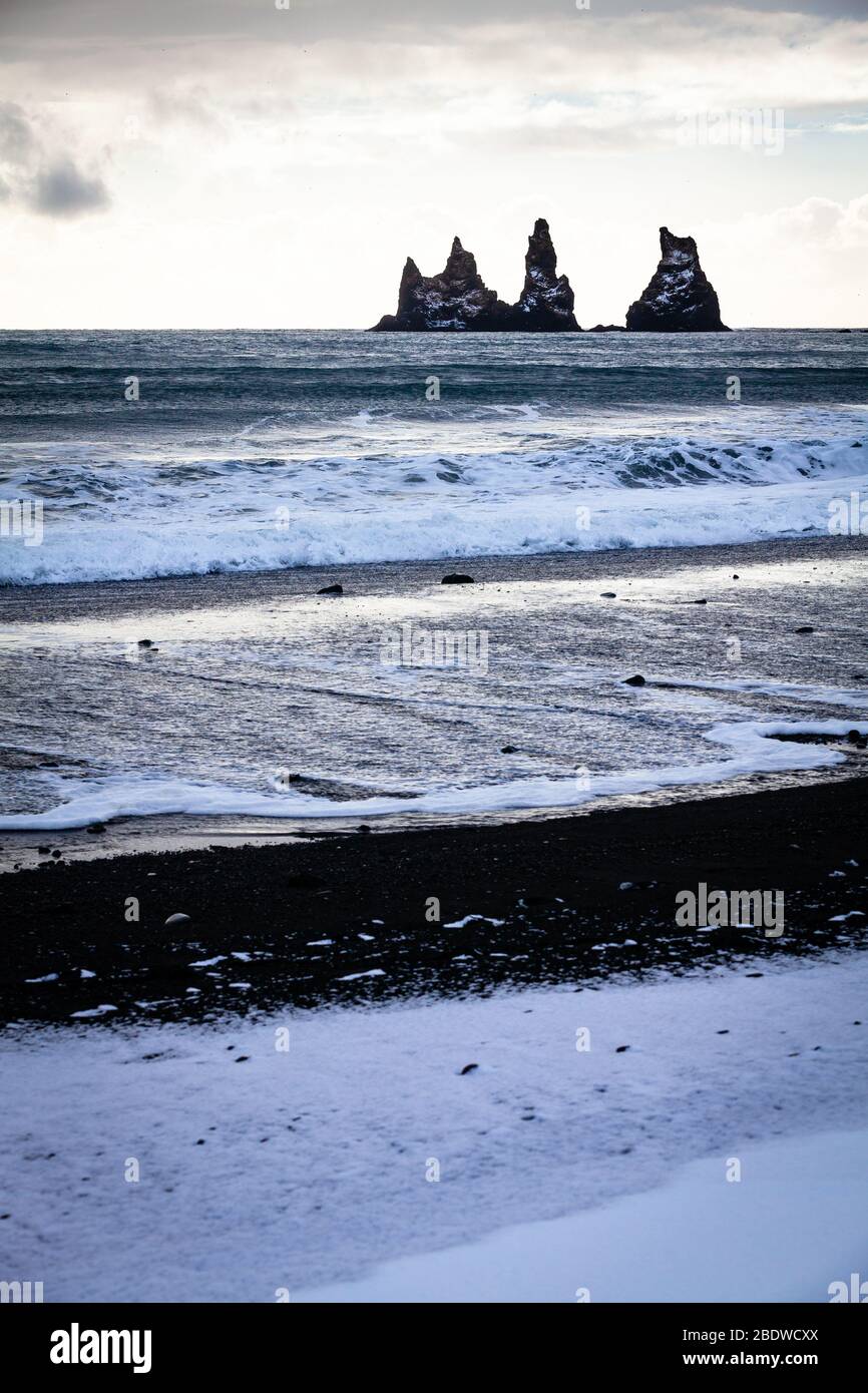 Les cheminées de mer de basalte de Reynisdrangar et les falaises de Reynisfjall recouvertes de neige en hiver à Vík í Mýrdal sur la côte sud de l'Islande Banque D'Images