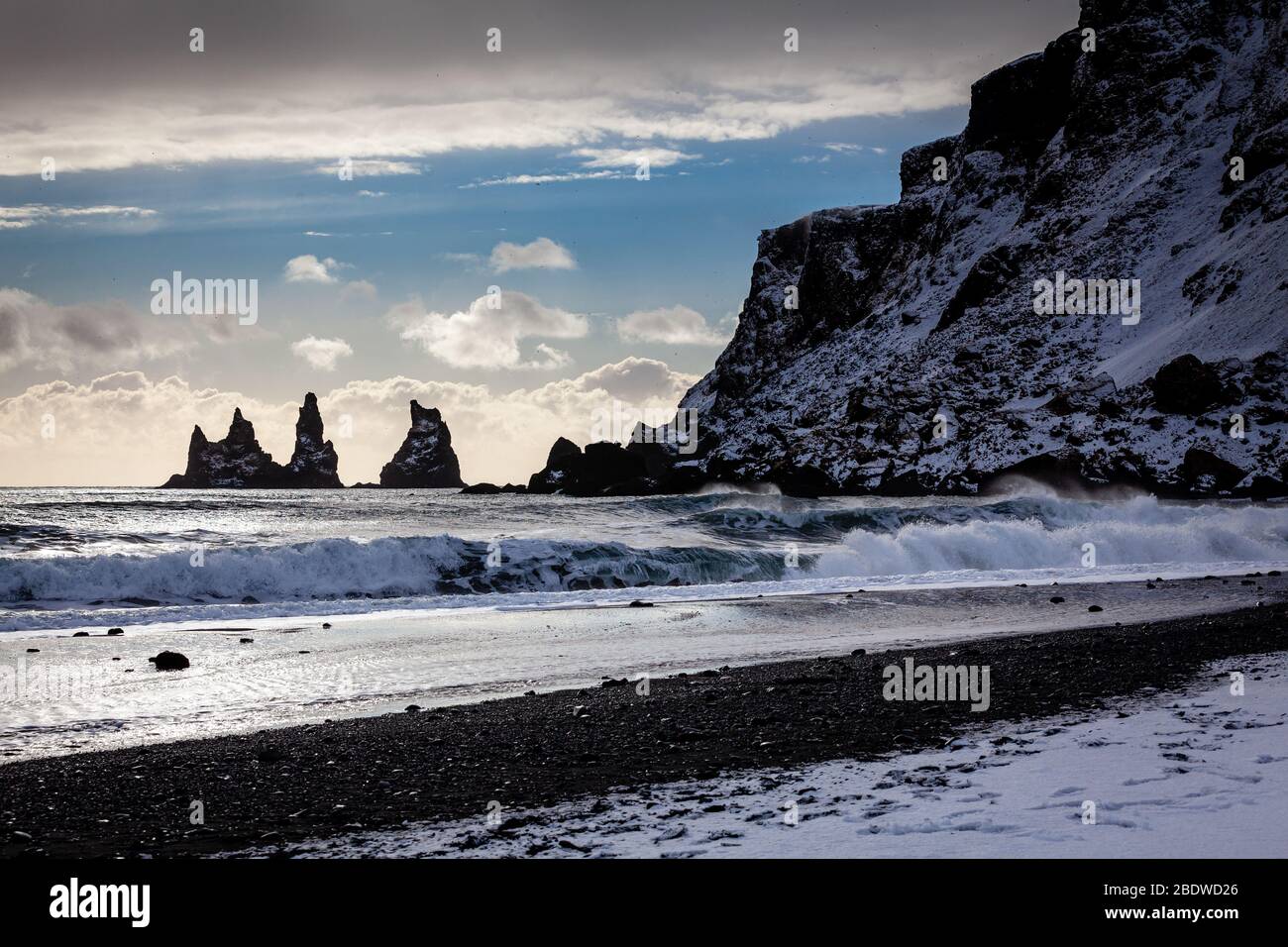 Les cheminées de mer de basalte de Reynisdrangar et les falaises de Reynisfjall recouvertes de neige en hiver à Vík í Mýrdal sur la côte sud de l'Islande Banque D'Images