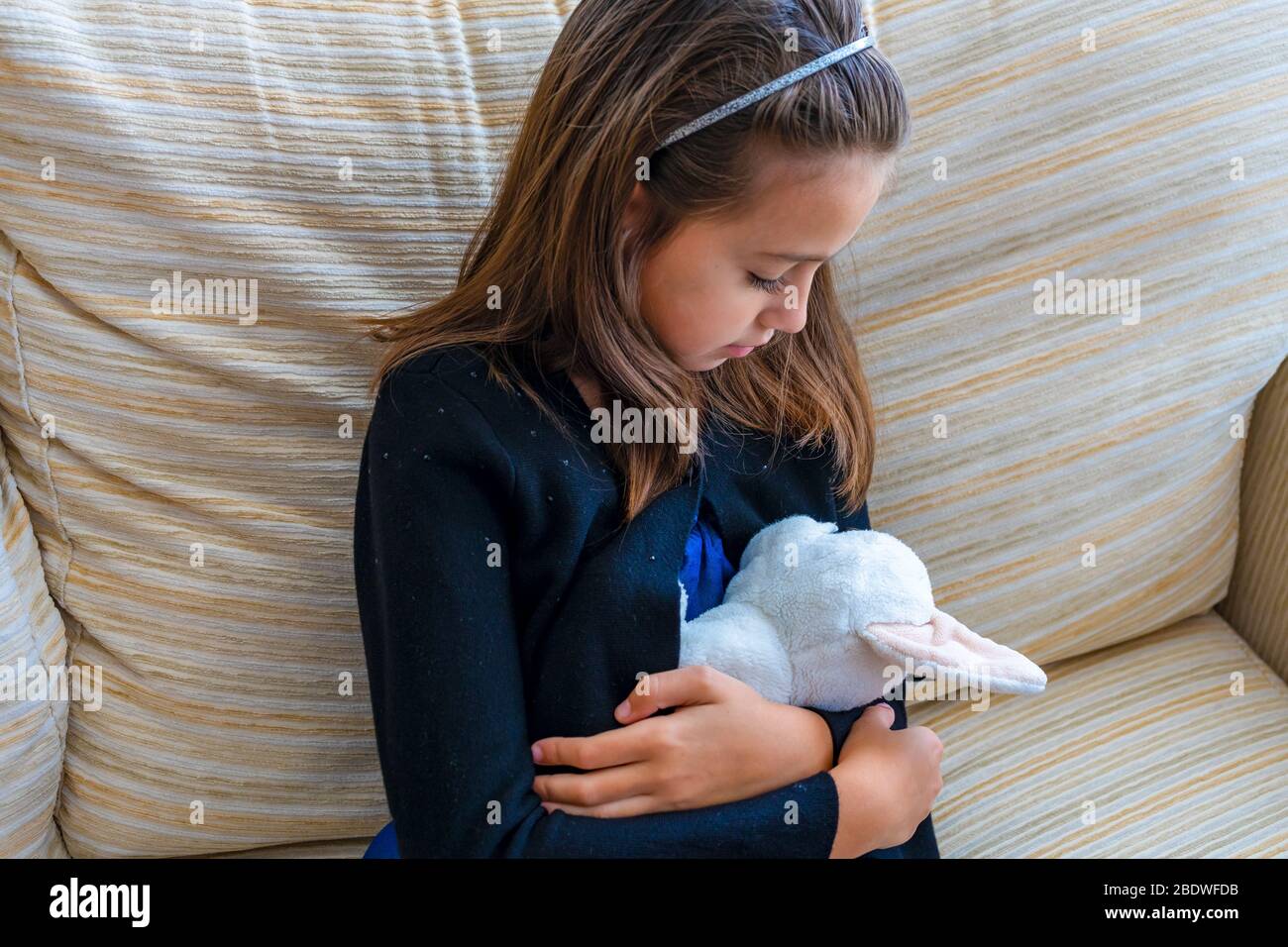 Petite fille avec une veste noire et un bandeau jouant avec son chien en  peluche noir et blanc sur le canapé blanc dans son salon Photo Stock - Alamy