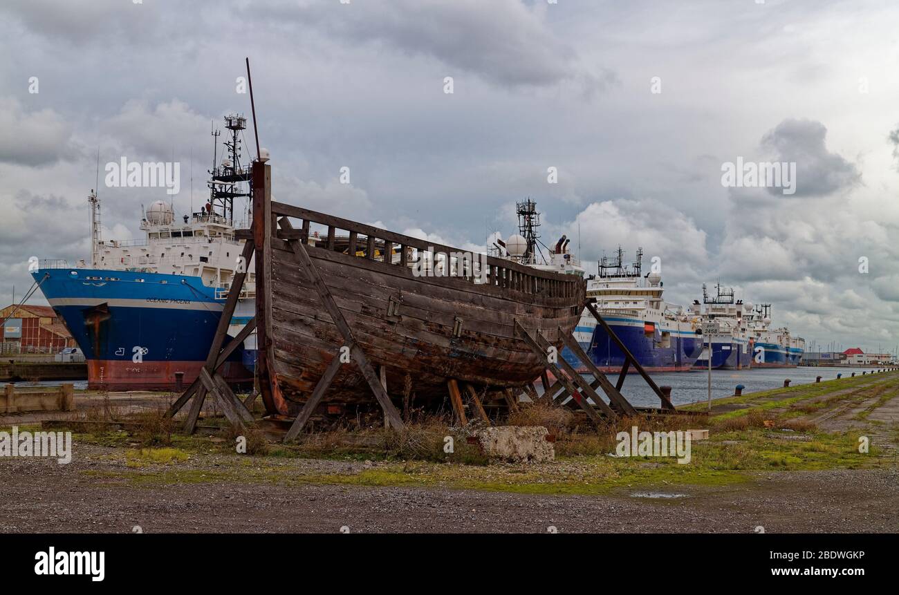 Un ancien bateau français en bois sur le Quayside devant les bateaux séismiques empilés à froid dans le port intérieur. Banque D'Images
