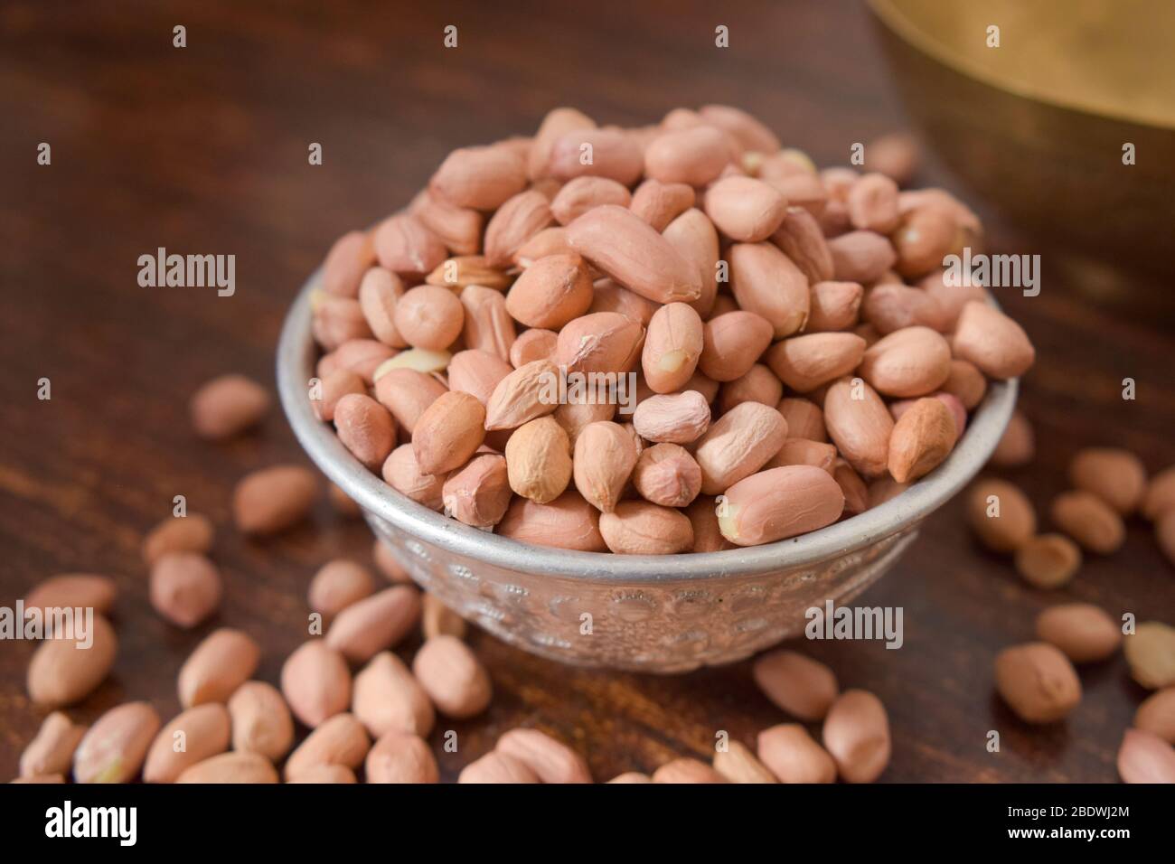 Arachides pelées dans un bol argent sur la vieille table en bois. Style rustique Banque D'Images