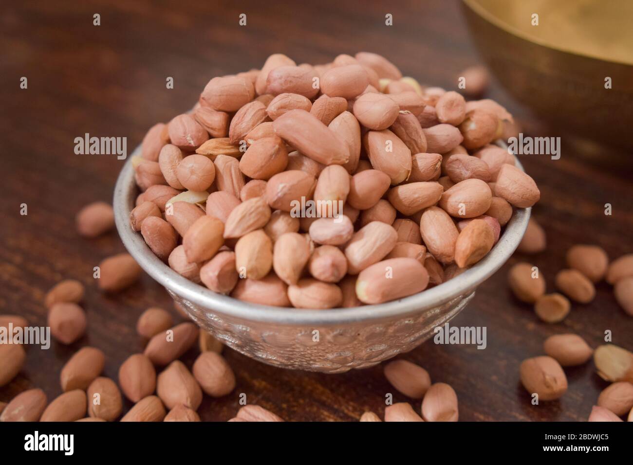 Arachides pelées dans un bol argent sur la vieille table en bois. Style rustique Banque D'Images