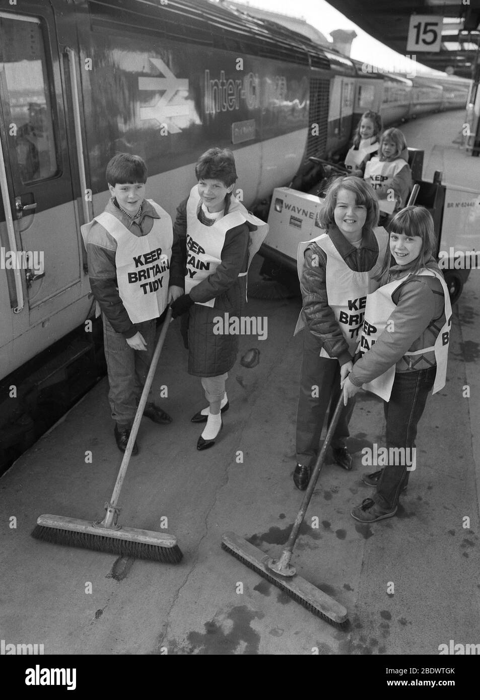 Les années 1980, les jeunes avec balais sur une plate-forme à l'intérieur d'une gare font leur petit peu pour garder la Grande-Bretagne bien rangée, Angleterre, Royaume-Uni. Dans les années 50, la Fédération nationale des instituts de femmes a fait campagne pour encourager les gens à rentrer chez eux et a ensuite adopté une motion pour "garder la Grande-Bretagne bien rangée". En 1960, une organisation caritative environnementale de cette mission a été officiellement enregistrée et travaille depuis pour promouvoir la sensibilisation et le changement de comportement lorsqu'il s'agit de litière et de litarement en Grande-Bretagne. Banque D'Images
