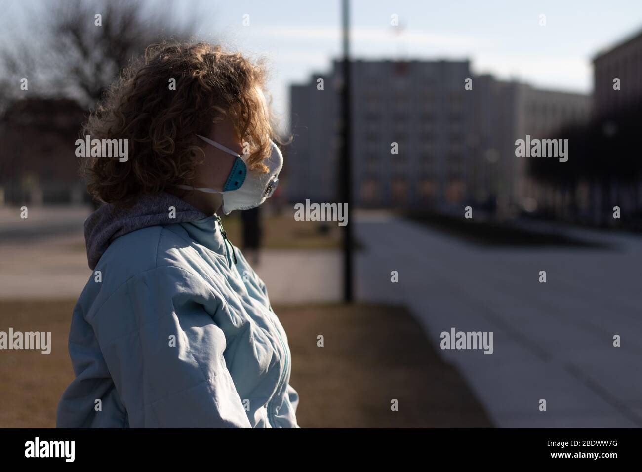 Vue latérale sur la jeune fille en plein air dans le centre-ville. Femme portant un respirateur médical. Masque de protection du visage. Espace de copie Banque D'Images