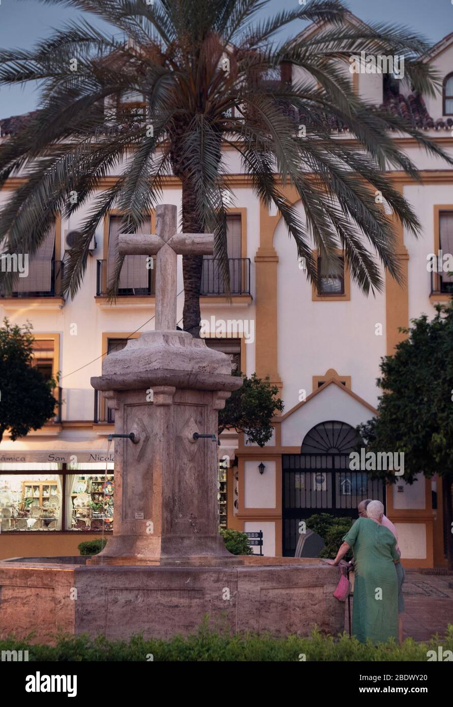 Les habitants de la région se tenant près d'une fontaine sur la place de l'église, plaza de la Iglesias, Marbella vieille ville, Espagne. Banque D'Images