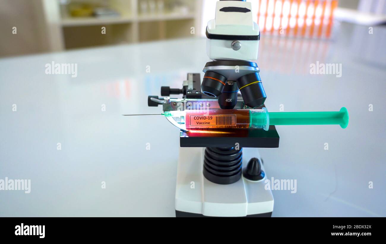 Regardez de plus près le microscope noir avec le vaccin contre le coronavirus à l'intérieur de la seringue Banque D'Images