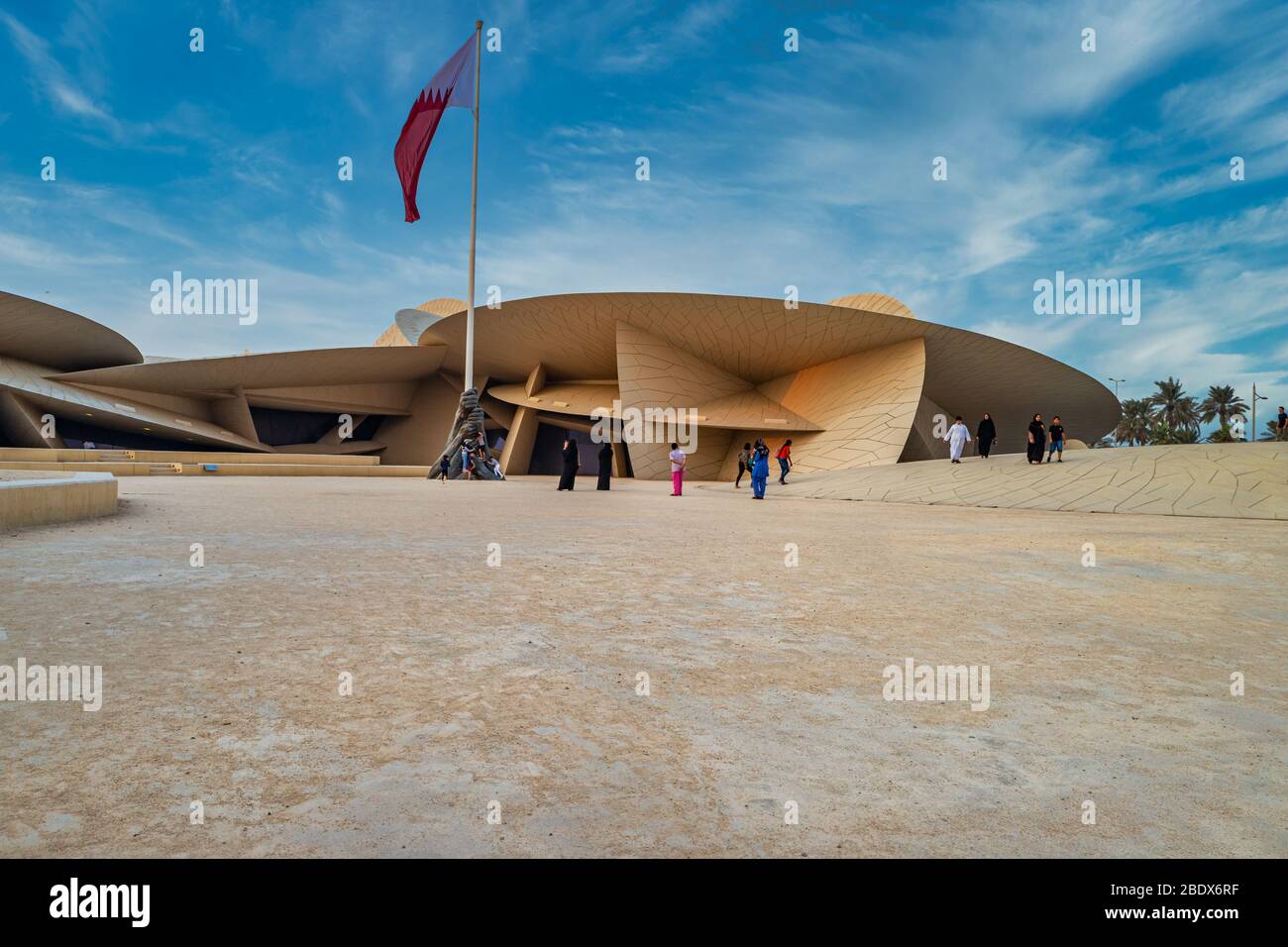 Musée national du Qatar (Desert rose) À Doha, Qatar, vue extérieure sur la lumière du jour avec drapeau du Qatar et nuages dans le ciel Banque D'Images