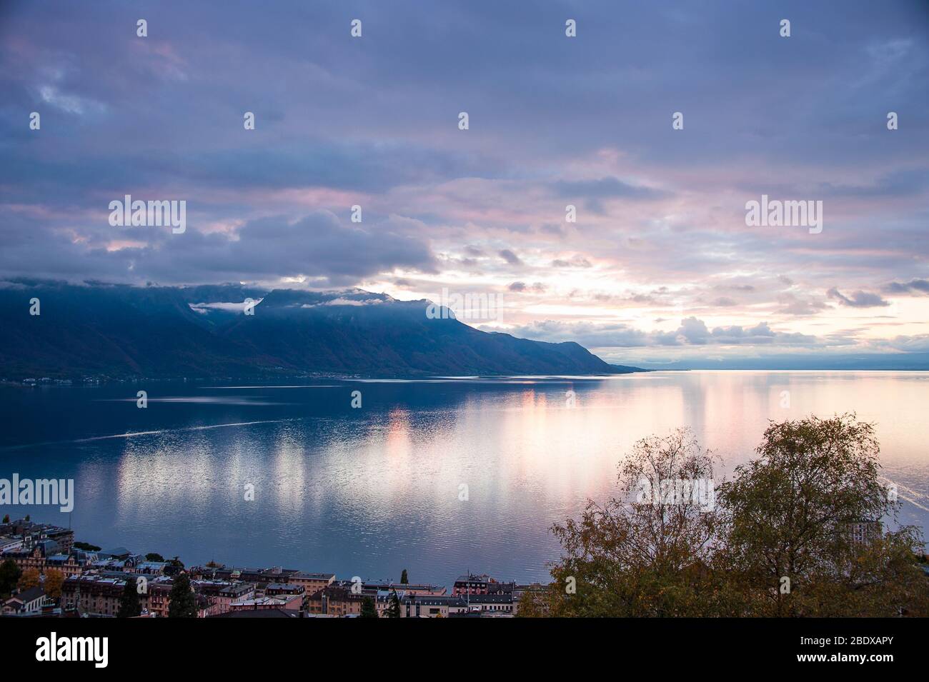 Magnifique coucher de soleil sur le lac de Genève, Suisse. La lumière solaire réfléchie sur l'eau, ciel dramatique dans une scène alpine. Banque D'Images