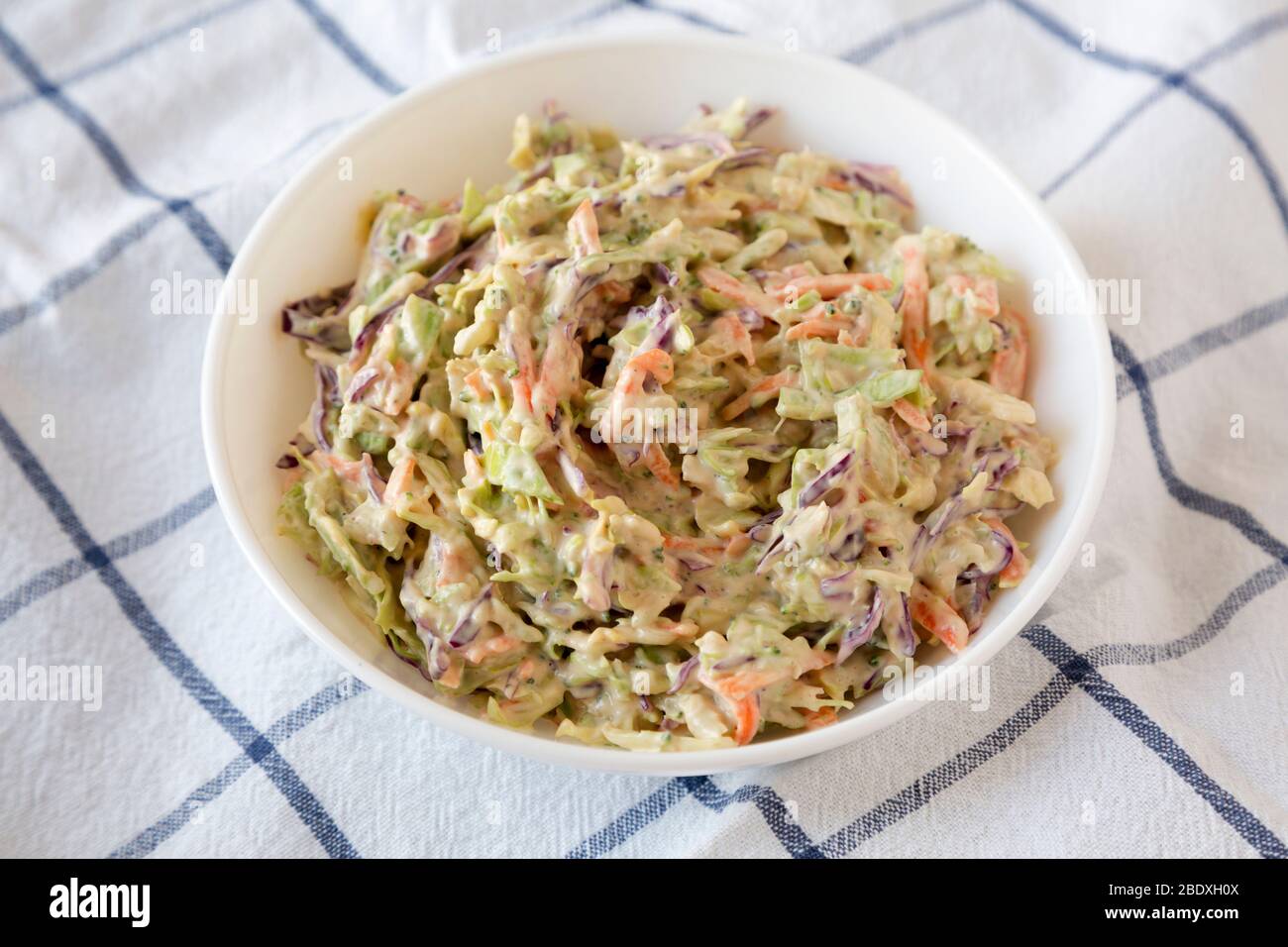 Creamy Broccoli Slaw maison dans un bol blanc sur tissu, vue latérale. Gros plan. Banque D'Images