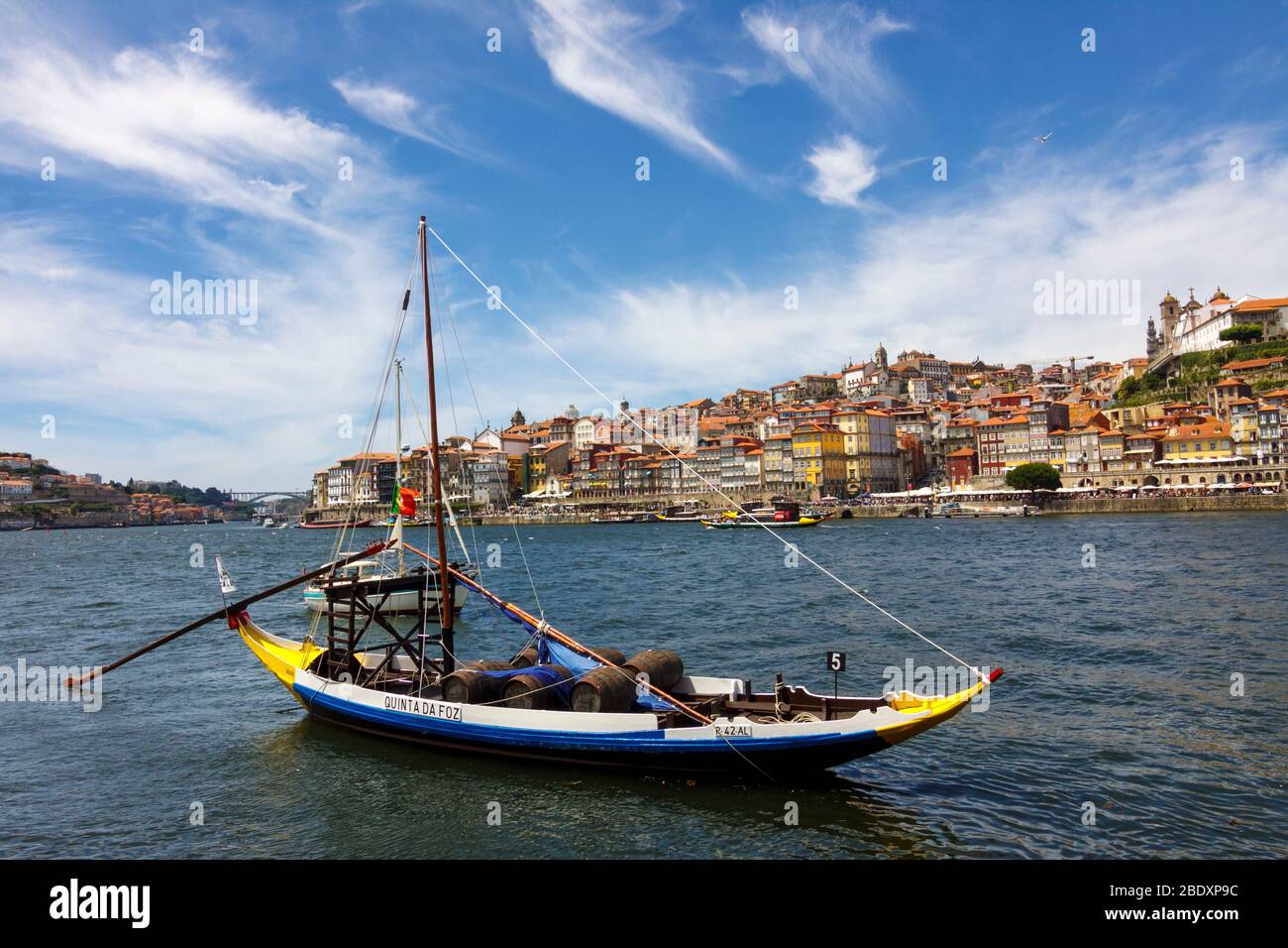 Porto, Portugal : un bateau traditionnel chargé de fûts de vin est amarré sur le fleuve Douro en face de la vieille ville de la rive. Banque D'Images