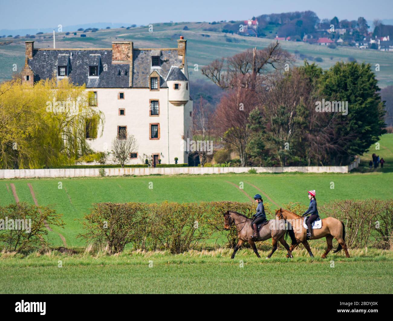 Les femmes qui font du cheval à cheval après le style baronnial écossais fortifié Ballencrieff House, East Lothian, Scotland, Royaume-Uni Banque D'Images