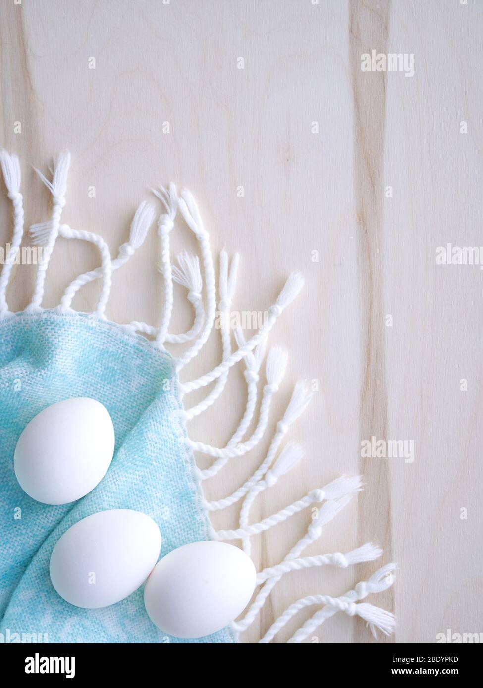 Oeufs blancs et bruns de Pâques sur fond bleu clair et bois avec décoration de fleurs. Banque D'Images