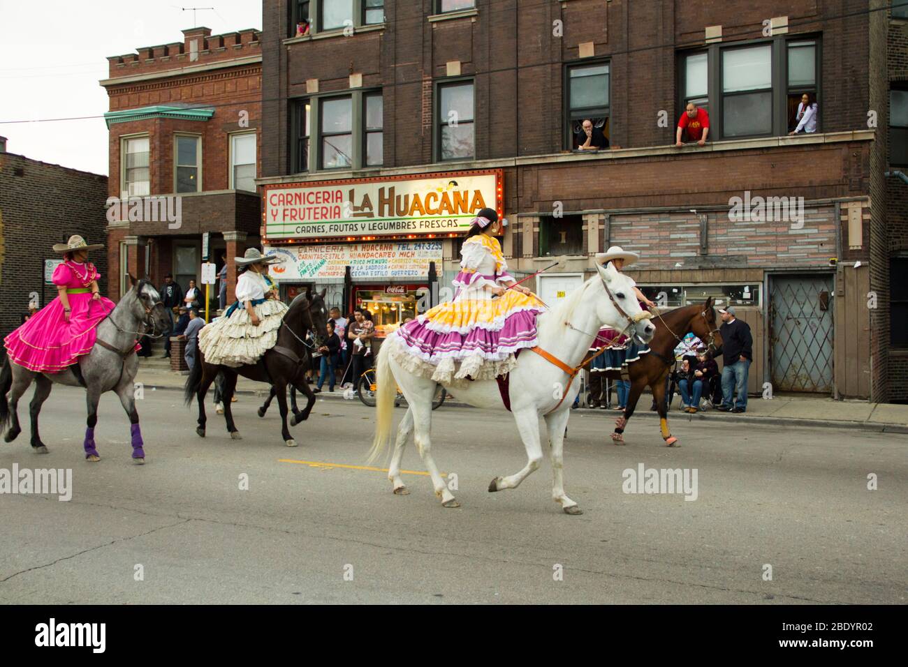 Femmes dans des robes colorées qui s'équestres sur des chevaux sur le défilé de rue, Pilsen, Chicago, Illinois, États-Unis Banque D'Images