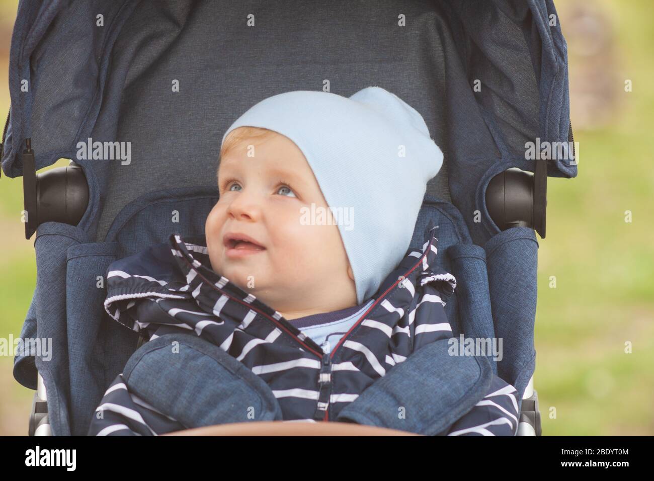 Une mère avec de longs cheveux maintient doucement son petit fils dans ses bras. Photo dans le parc avec lumière naturelle Banque D'Images