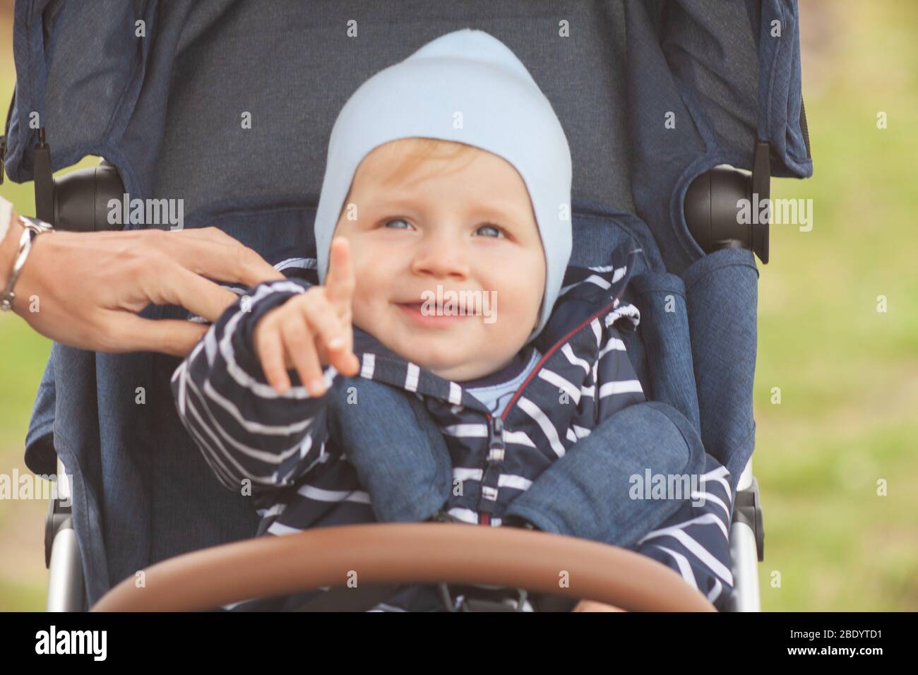 Une mère avec de longs cheveux maintient doucement son petit fils dans ses bras. Photo dans le parc avec lumière naturelle Banque D'Images