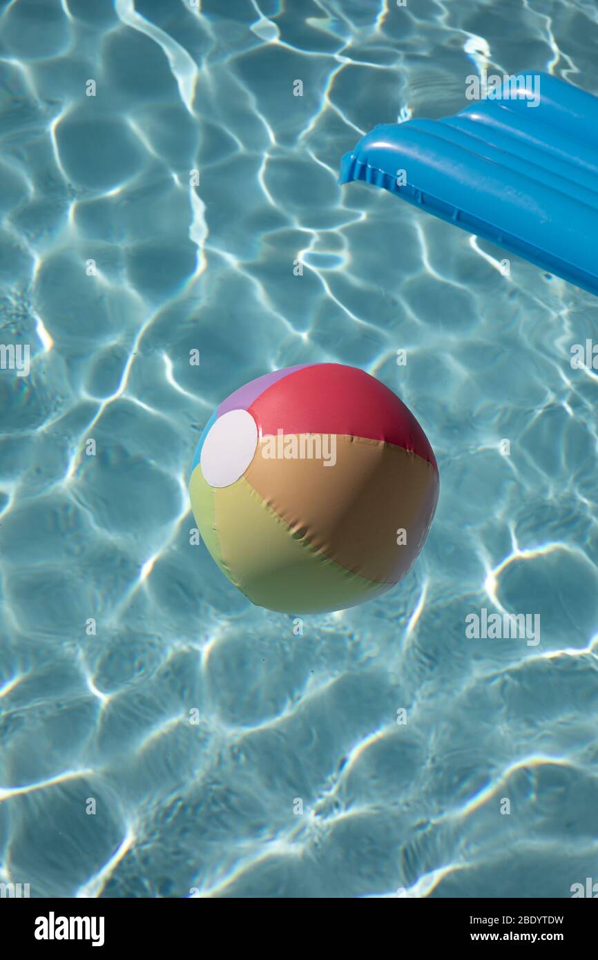 scruter avec de l'eau bleu clair un radeau de soufflage et de la boule de plage multicolore Banque D'Images