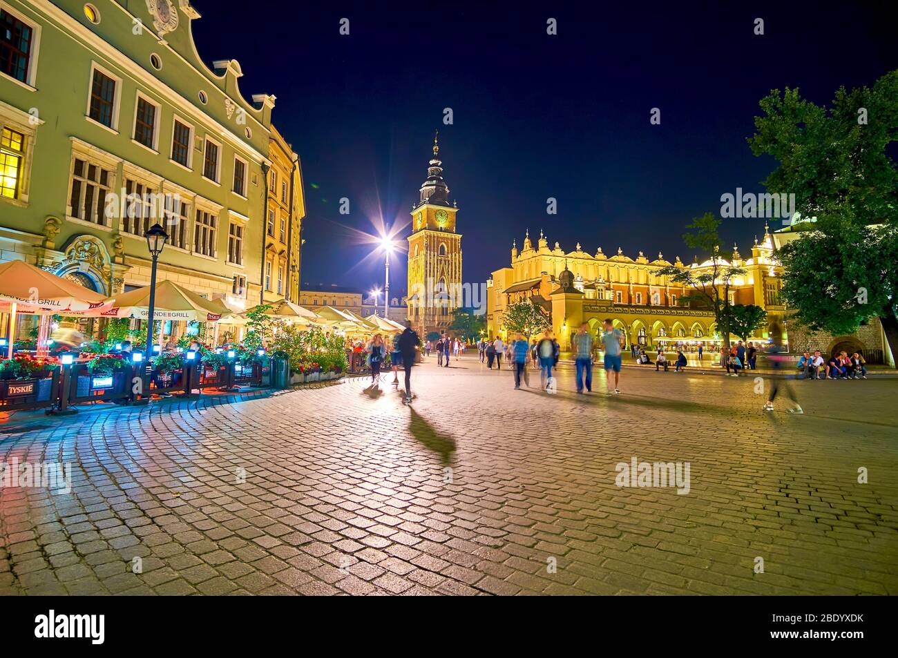 CRACOVIE, POLOGNE - 12 JUIN 2018: La place du marché principal la nuit, on marche le long de la ligne de cafés en plein air, d'autres dînent à l'intérieur d'eux, le 12 juin i Banque D'Images