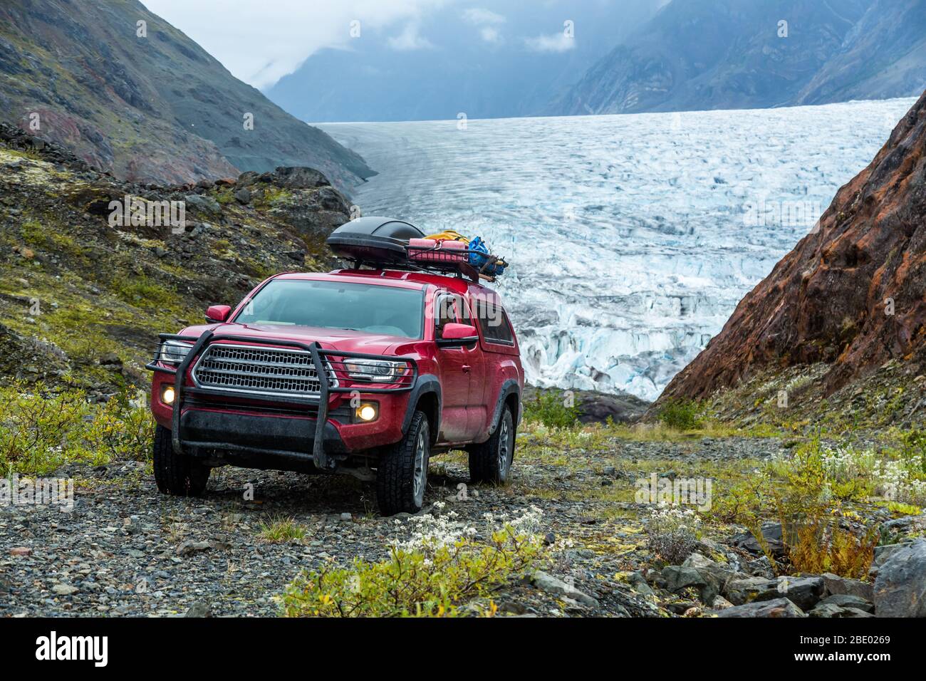 Camion de ramassage à quatre roues motrices rouge sur une route en gravier raide et étroite surplombant un glacier en Colombie-Britannique éloignée près du territoire du Yukon et de la région de l'Alaska Bo Banque D'Images
