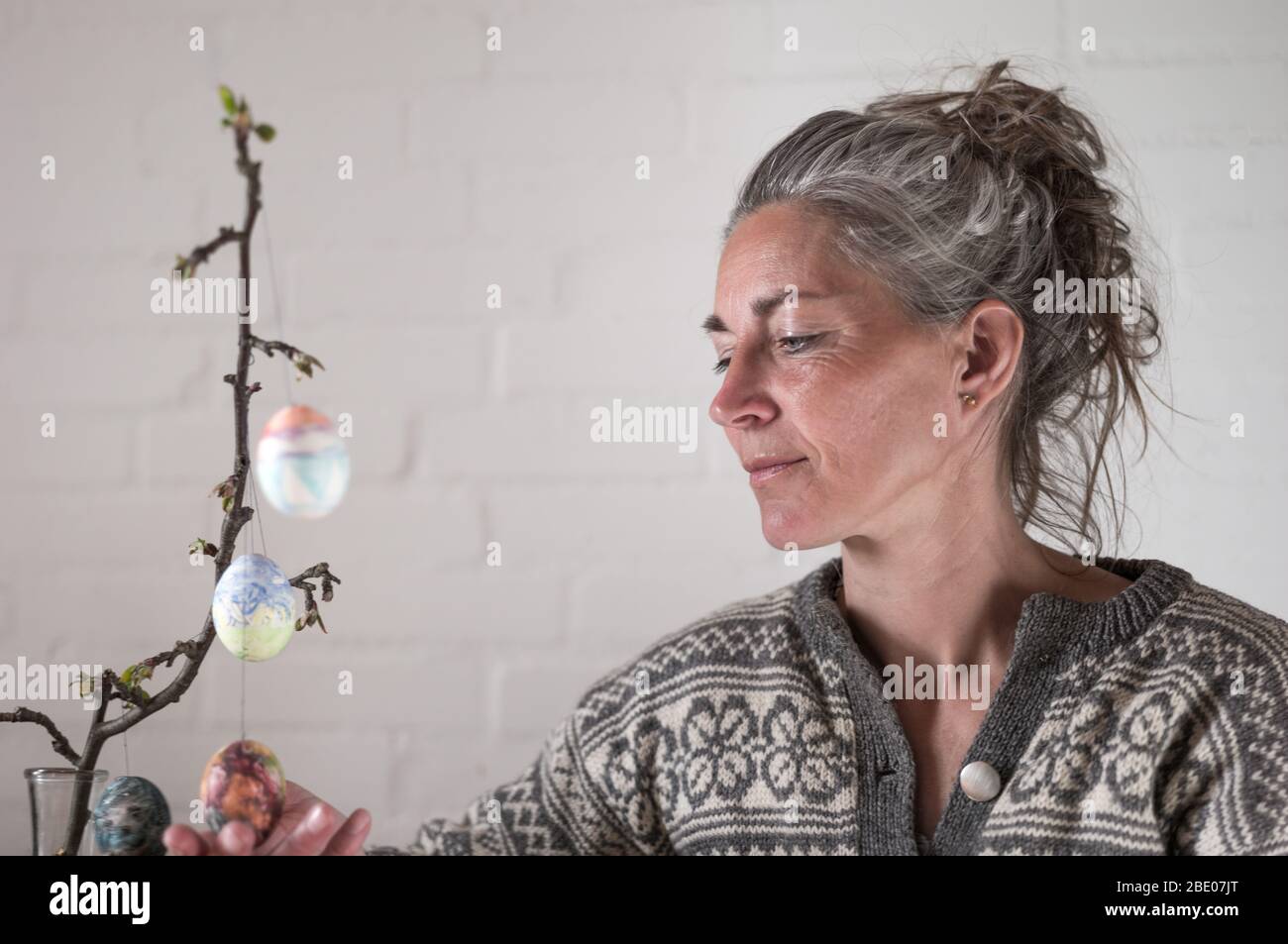 Femme mûre avec cheveux gris et pull gris avec œufs de pâques Banque D'Images