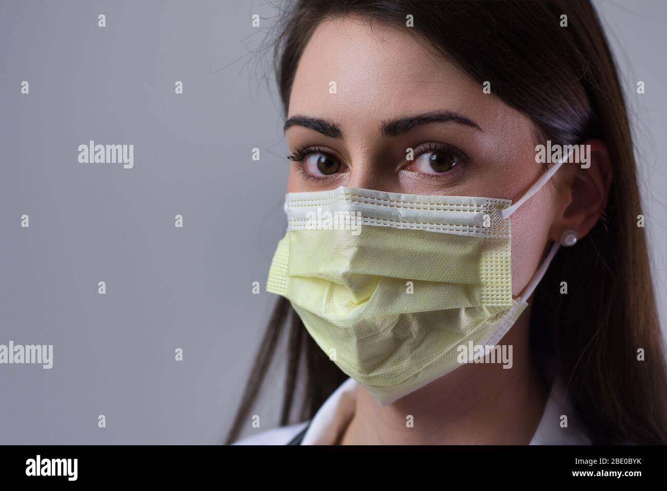 Femme hospitalisée portant un masque jaune. Yeux visibles sur le couvercle. Isolé sur fond gris. Banque D'Images