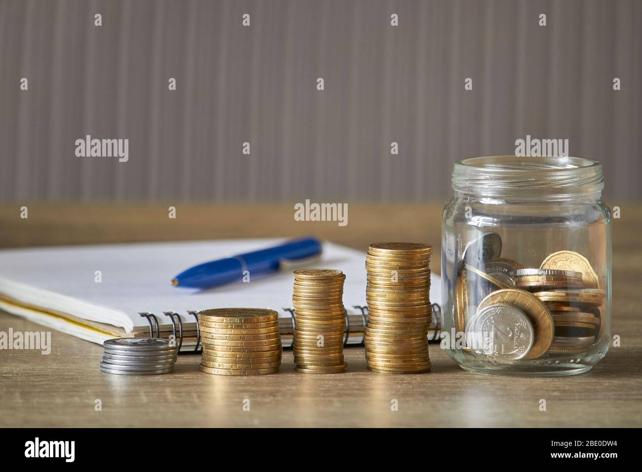 Rangées de pièces de monnaie et de pièces de monnaie en pot sur table en bois avec fond gris, concept d'économie d'argent Banque D'Images