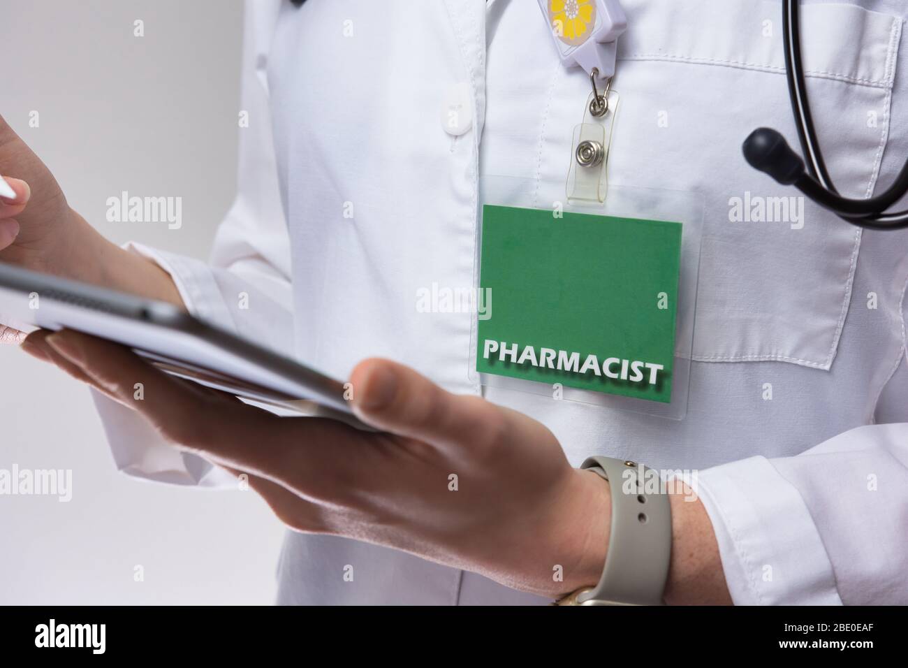 Un pharmacien proche utilisant la technologie pour prendre soin du patient. Pharmacien femelle isolé sur la paroi grise. Banque D'Images