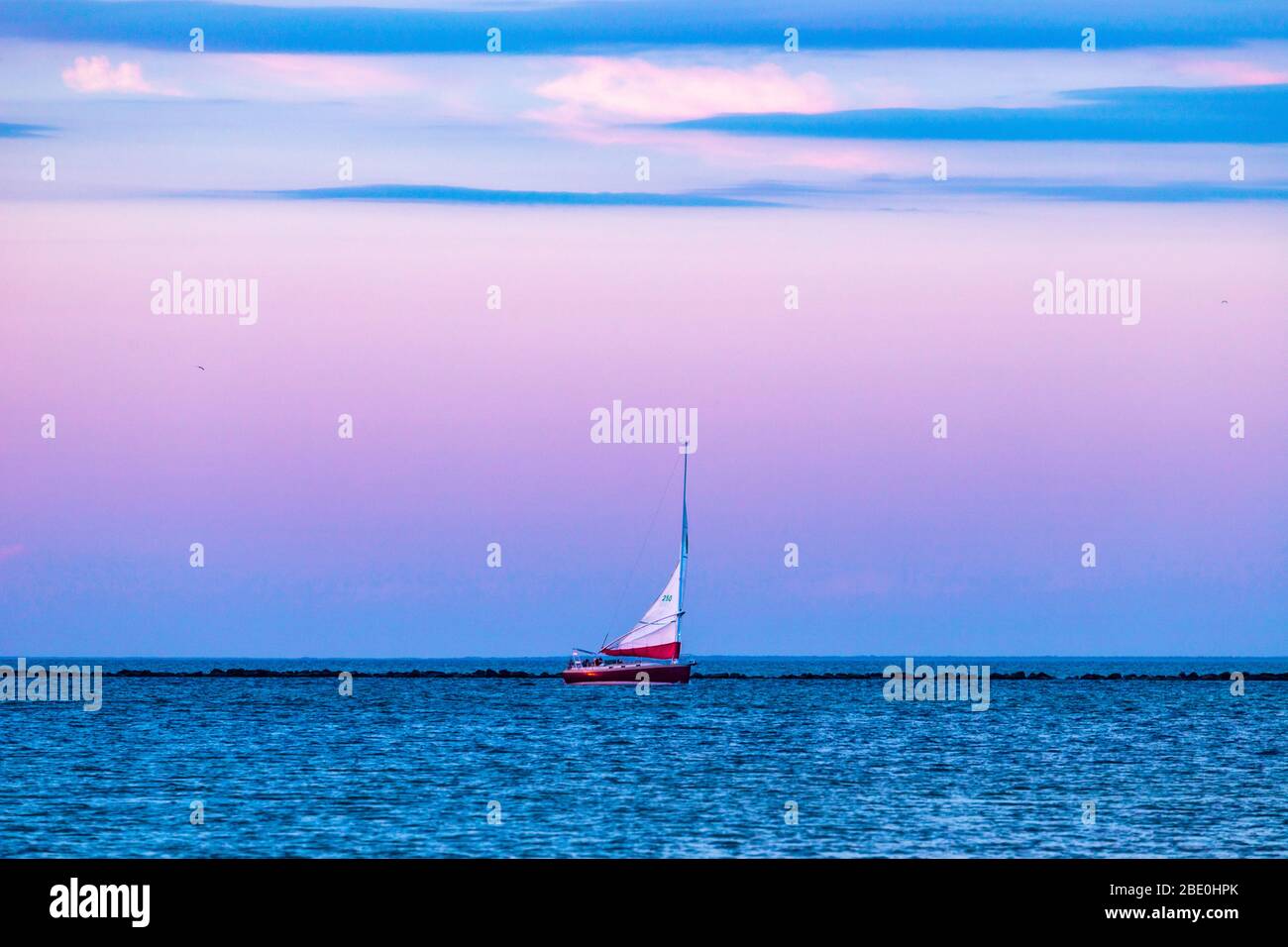 Voilier blanc naviguant dans le port de Nantucket sous un ciel violet. Banque D'Images