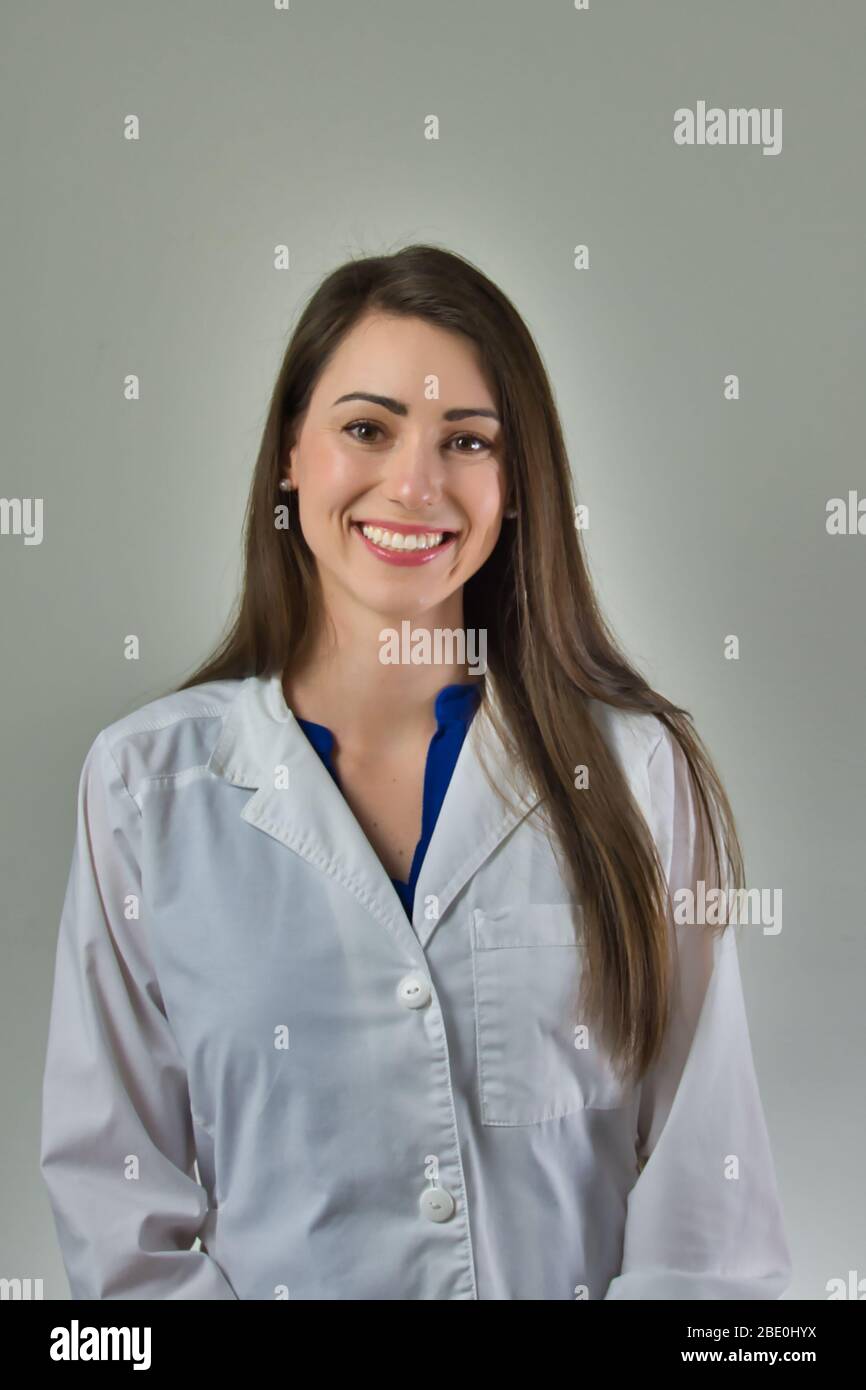 Femme professionnel de la santé en manteau blanc isolé sur mur gris. Tête et épaules visibles. Banque D'Images