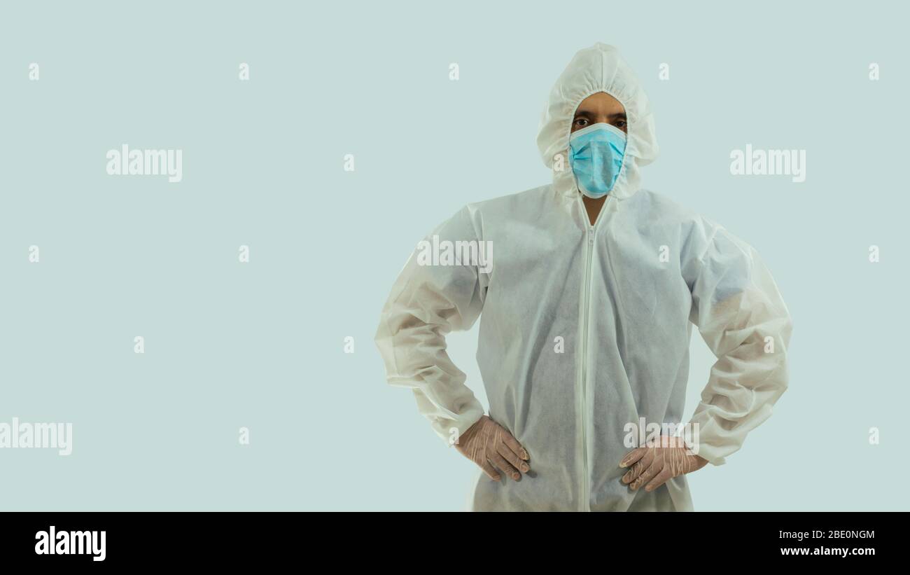 Vue avant du médecin avec masque bleu et costume bioprotecteur avec mains sur la taille sur fond blanc Banque D'Images