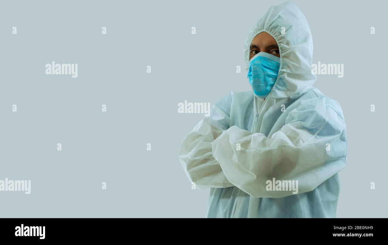 Vue latérale du médecin avec masque bleu et costume bioprotecteur blanc avec bras croisés sur fond blanc Banque D'Images