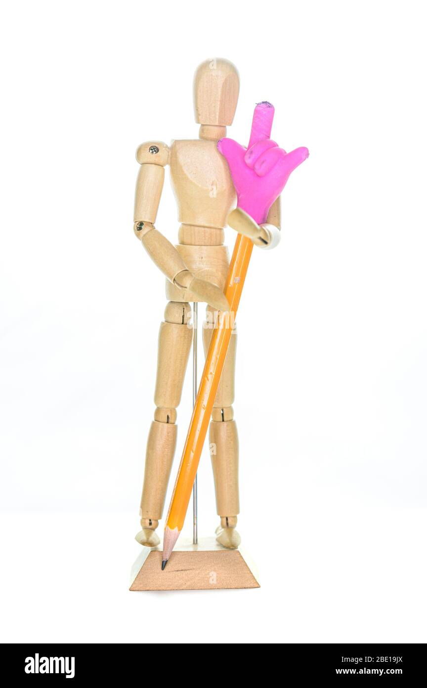 Petit mannequin en bois tenant un crayon avec une main de gomme, ce qui fait le signe des cornes, isolé sur un fond blanc Banque D'Images