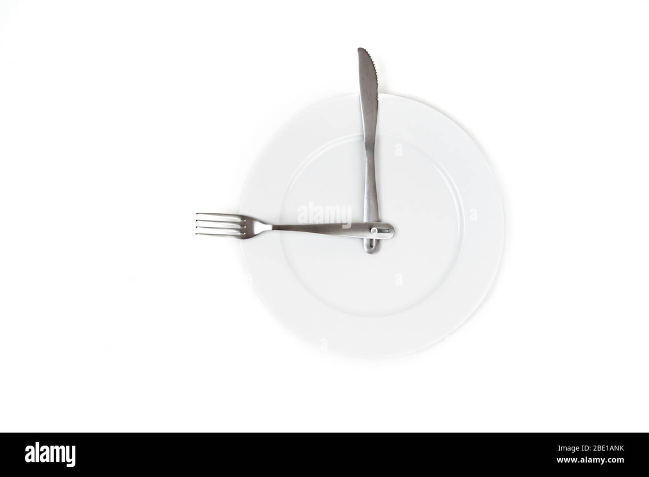 Fourche et couteau en acier inoxydable sur une plaque blanche ressemblant à une horloge isolée sur blanc. Concept de temps à manger Banque D'Images