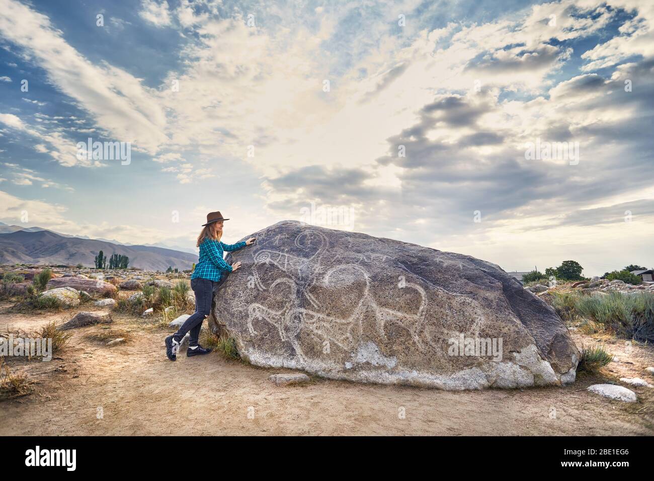 Fille de tourisme en chemise à carreaux dans le musée en plein air près de stone ancient petroglyph de chèvres à Kirghizistan Banque D'Images