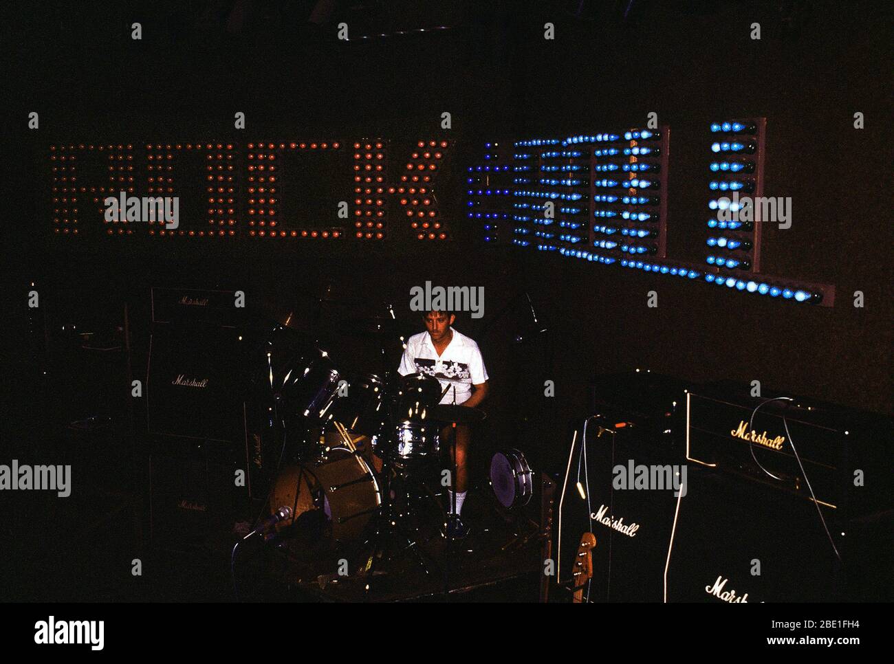 1981 - Un musicien assis à sa batterie dans l'obscurité d'une salle de concert avant le début d'un concert de rock and roll Banque D'Images