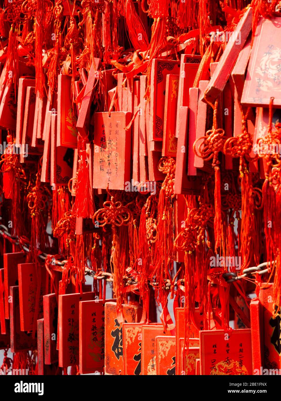 Des plaques de vœux rouges avec des franges décoratives sont suspendues densément dans un temple chinois traditionnel, portant des prières, des souhaits et des bénédictions pour la bonne fortune Banque D'Images