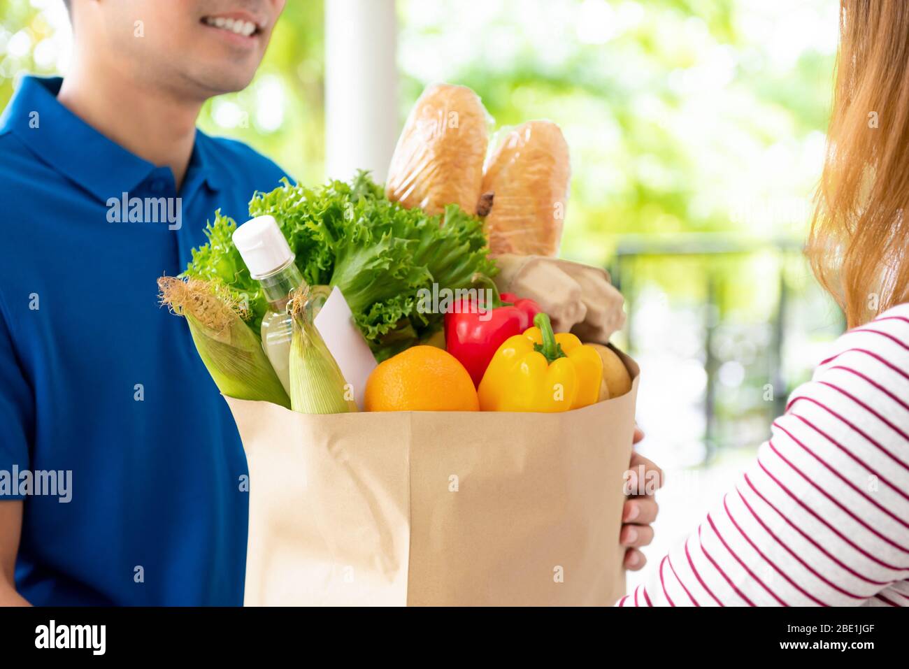 Les produits alimentaires livrés au client à la maison par un homme de livraison, pour le concept de service alimentaire en ligne Banque D'Images
