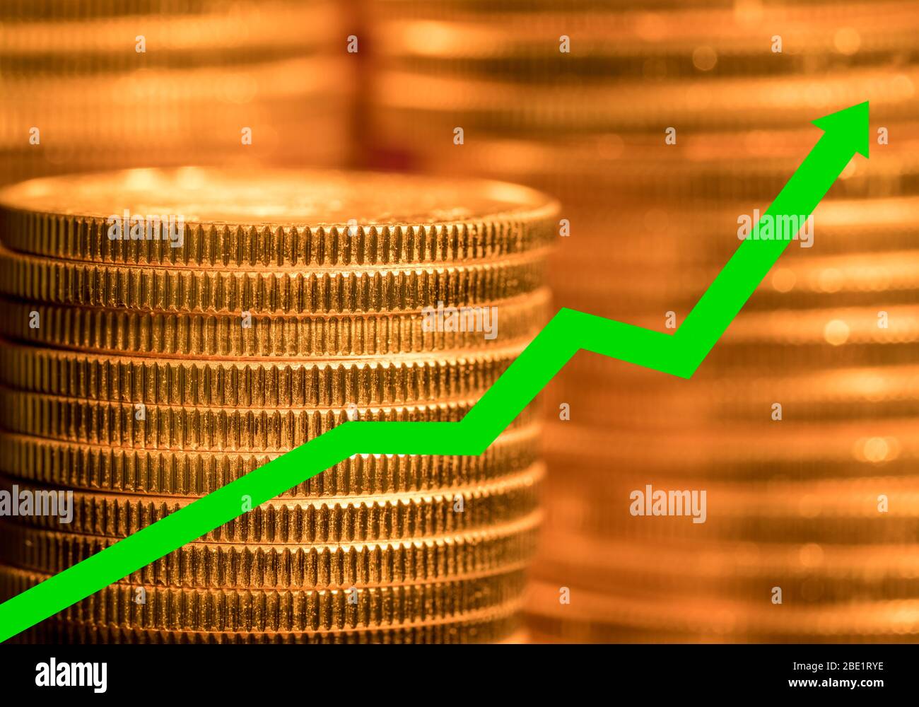 De nombreuses pièces d'or empilées avec une flèche verte pour illustrer l'augmentation du prix de l'or pur comme investissement Banque D'Images